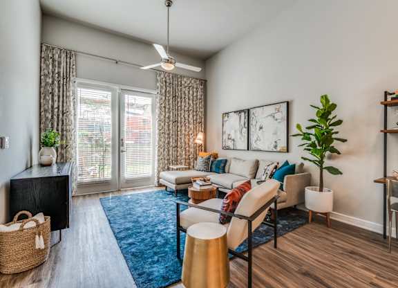 A living room with a blue rug and a ceiling fan.