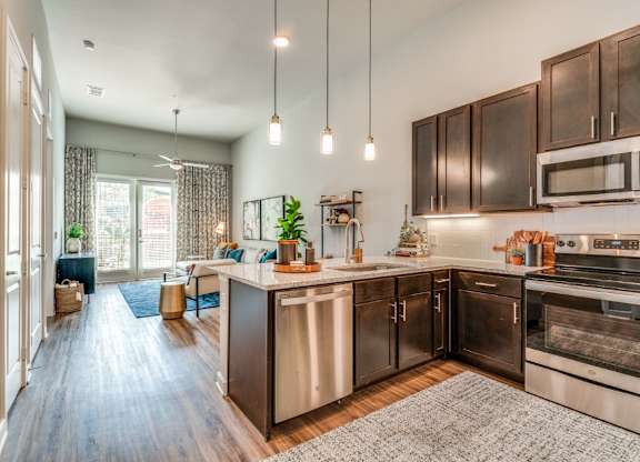 A modern kitchen with dark wood cabinets and stainless steel appliances.