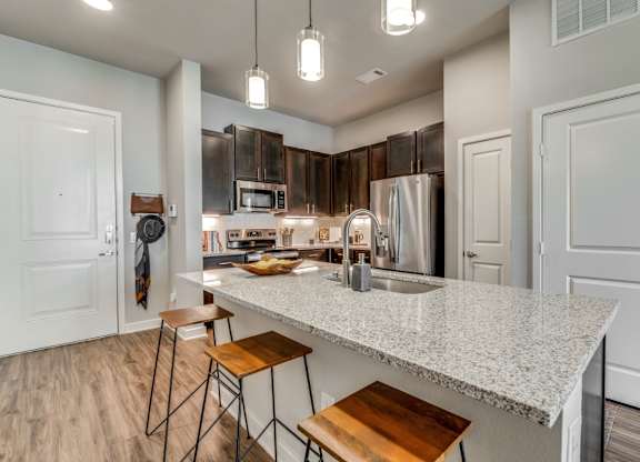 A kitchen with a white countertop and wooden stools.