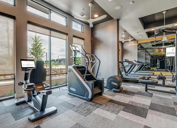 A JEFFERS brand treadmill is in a gym with a view of the outdoors.