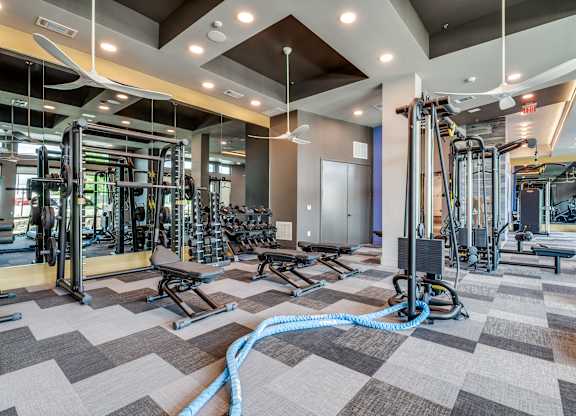 A gym with a variety of equipment including treadmills, weights, and exercise machines.