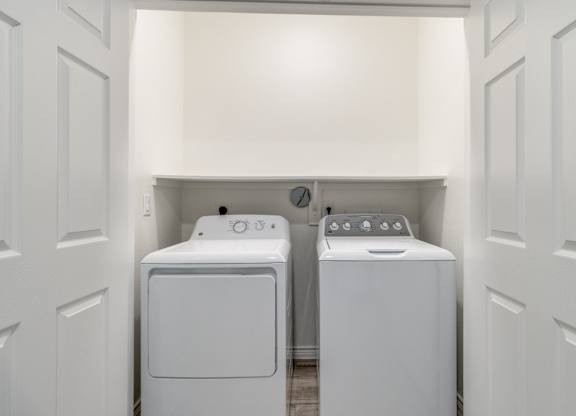 a washer and dryer in a laundry room with white walls and white doors