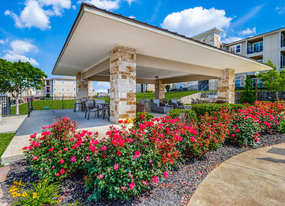 a patio with flowers and a table and chairs in front of a building