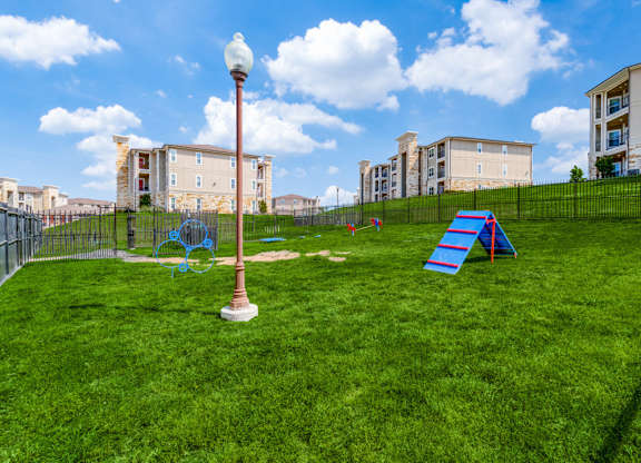 a playground on the grass with apartments in the background