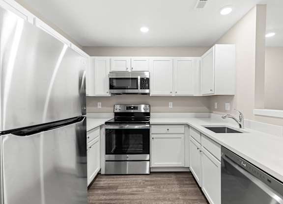 a white kitchen with stainless steel appliances and white cabinets