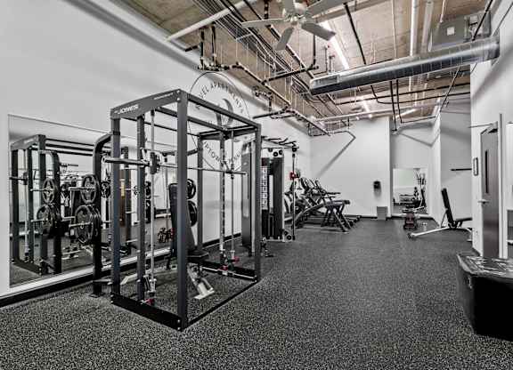 A gym with a variety of equipment including a squat rack, bench, and weights.