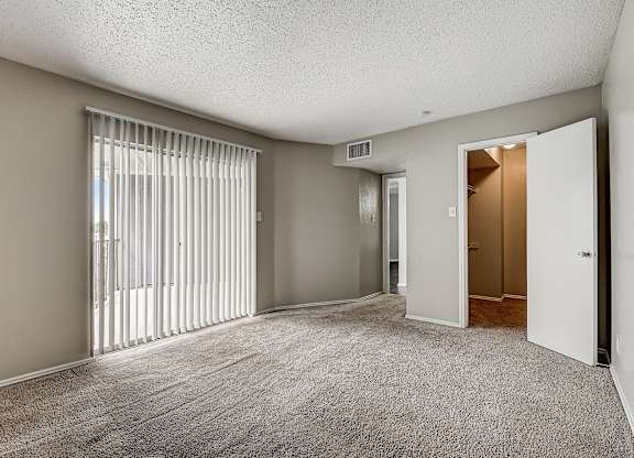 a bedroom with a sliding glass door and carpeted flooring
