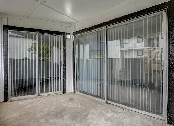 a patio with two sliding glass doors and a tree in the background