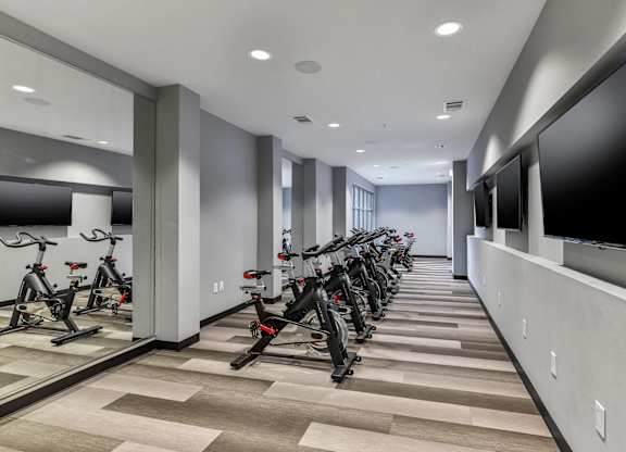 A row of exercise bikes are lined up in a room.