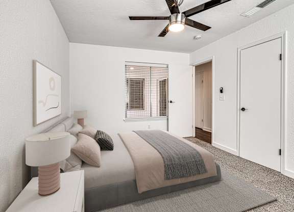 A bedroom with a bed, nightstand, and a ceiling fan.