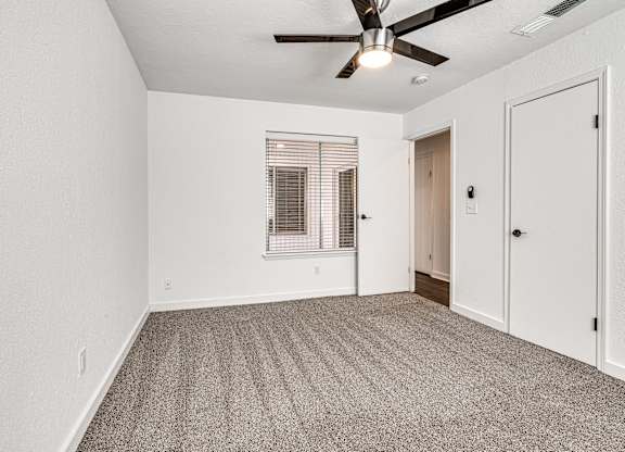 A room with a ceiling fan and carpeted floor.