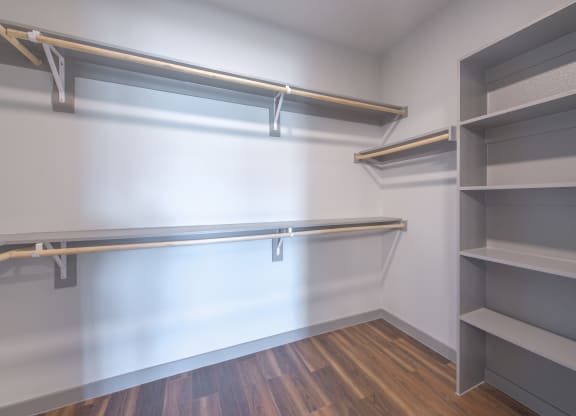a walk in closet with empty shelves and a white wall