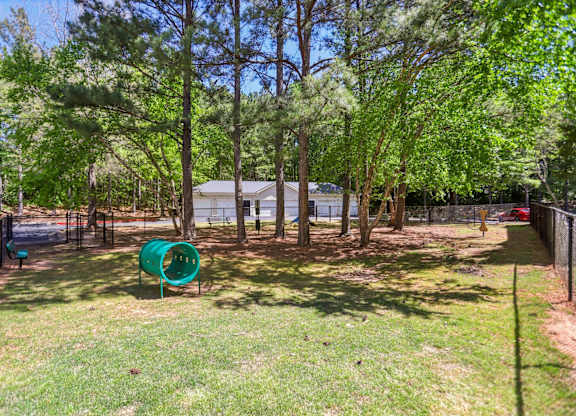 A green slide in a backyard surrounded by trees.