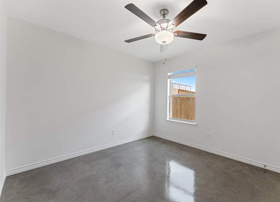 an empty room with a ceiling fan and a window