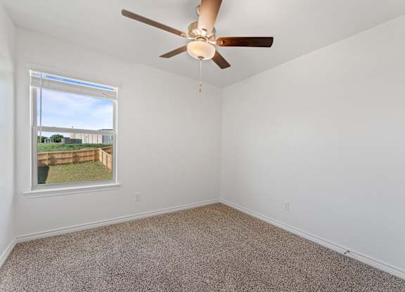 an empty room with a ceiling fan and a window