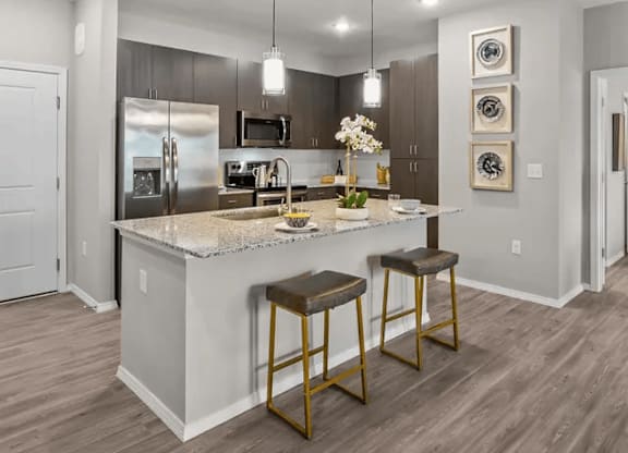 A modern kitchen with a marble countertop and stainless steel appliances.