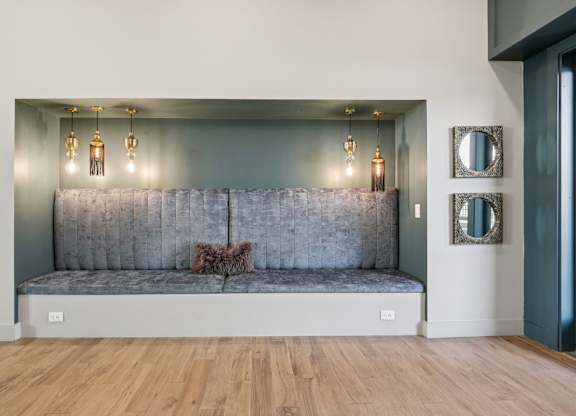 A grey couch with a pillow on it in a room with wooden floors.