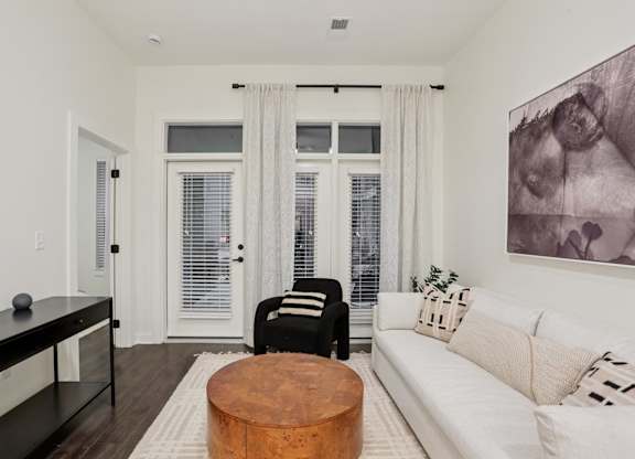 A living room with a white couch, a coffee table, and a painting on the wall.
