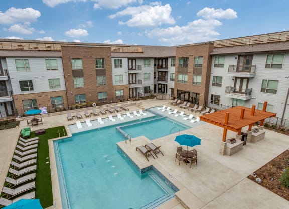 a resort style pool with lounge chairs and umbrellas in front of a building