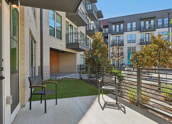 A balcony with a chair and a table with a view of a building.