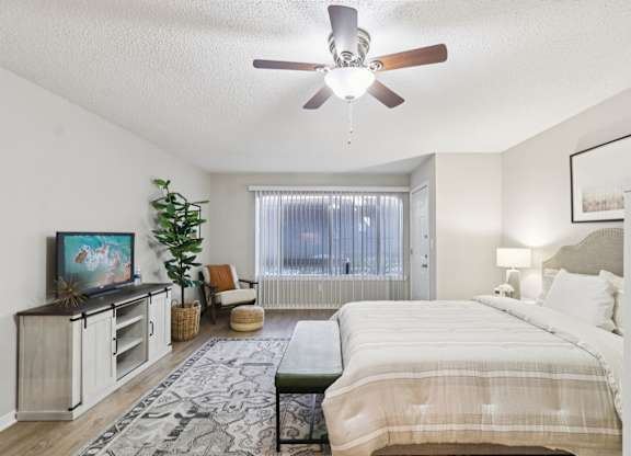 A bedroom with a bed, a television, and a plant.