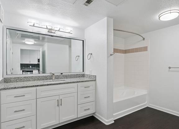 A white bathroom with a sink, mirror, and shower.