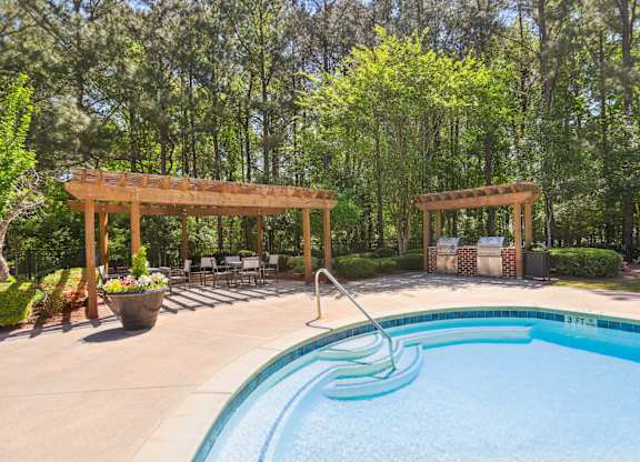A pool with a slide and a pergola in the background.