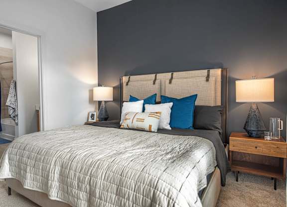 A bedroom with a large bed and a wooden nightstand.
