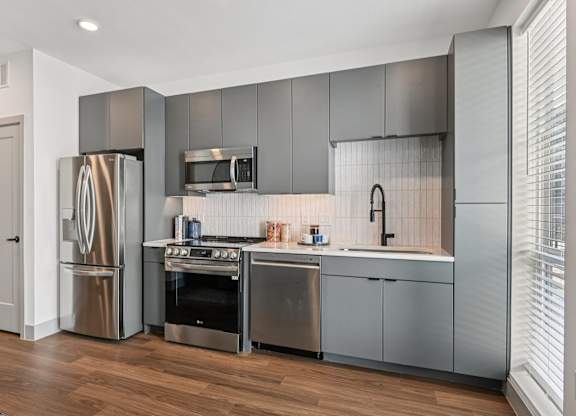 A modern kitchen with stainless steel appliances and wooden floors.