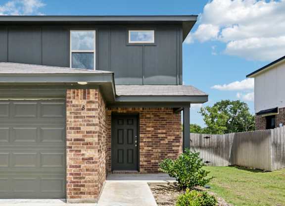 A modern house with a grey garage door and a brick wall.