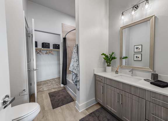 A bathroom with a toilet, sink, and mirror.