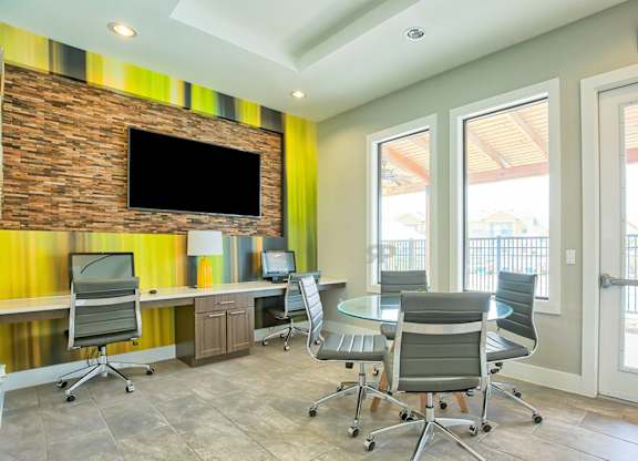 A conference room with a brick wall and a TV above the desk.