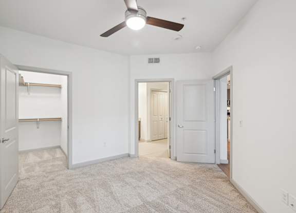 A room with a ceiling fan and carpeted floor.