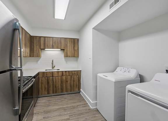 A kitchen with a refrigerator, a sink, and a washer and dryer.