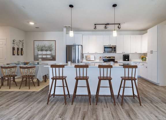 a kitchen and dining area with bar stools in a living room with a kitchen