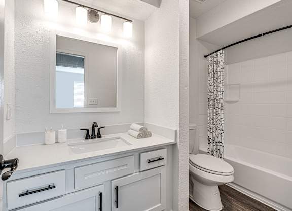 A white bathroom with a toilet, sink, and mirror.
