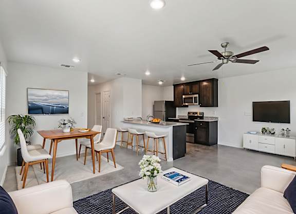 A modern living room with a dining area and kitchen in the background.