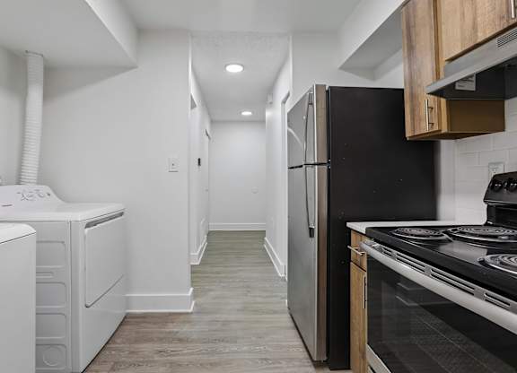 A black refrigerator sits next to a stove in a kitchen.