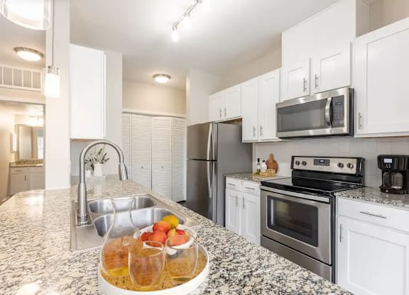 A kitchen with a granite countertop and stainless steel appliances.