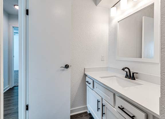 A white bathroom with a sink and mirror.