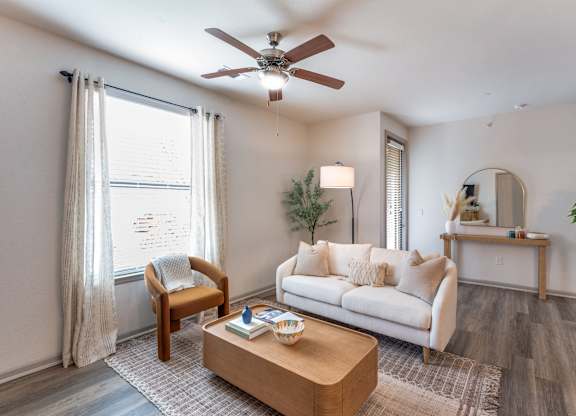 A living room with a white couch, a wooden coffee table, and a ceiling fan.