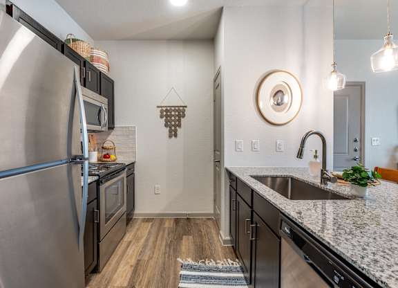 A modern kitchen with a stainless steel refrigerator and black cabinets.