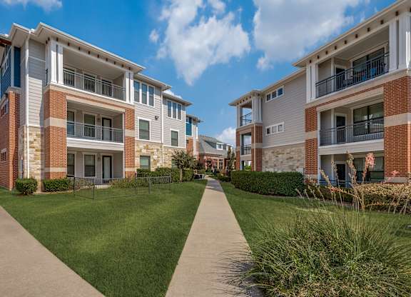 A row of modern apartment buildings with a walkway in between.