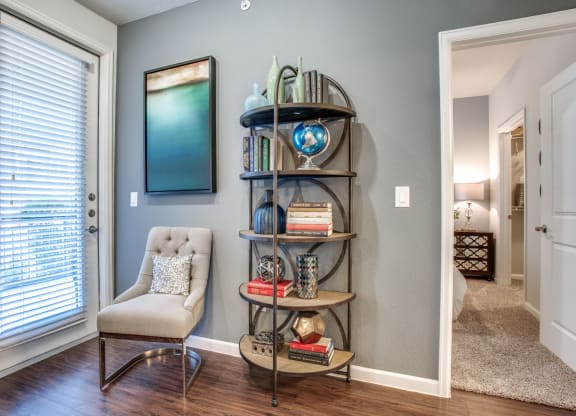 a living room with a chair and a shelf with books