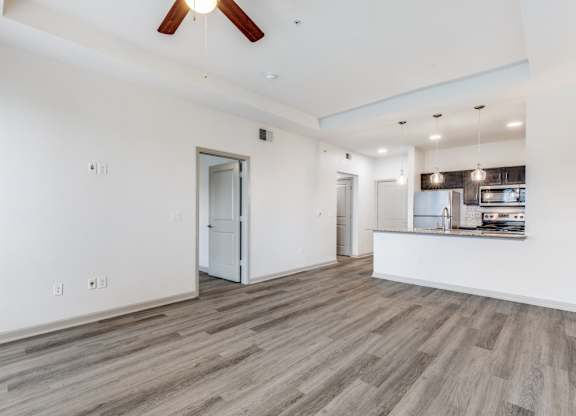 A spacious room with a ceiling fan and wooden flooring.