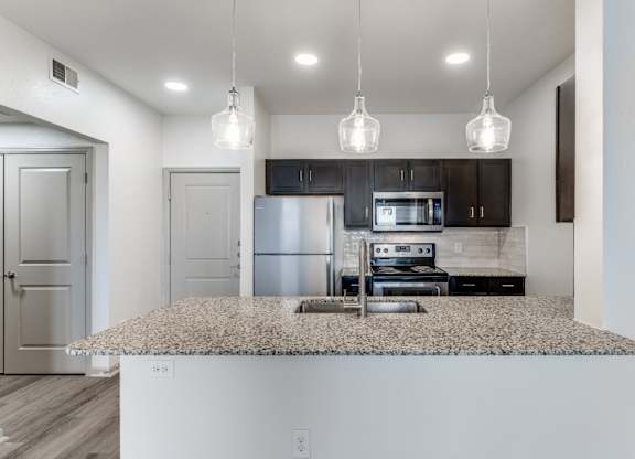 A kitchen with a granite countertop and a microwave above it.