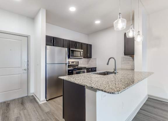 A kitchen with a granite countertop and stainless steel appliances.