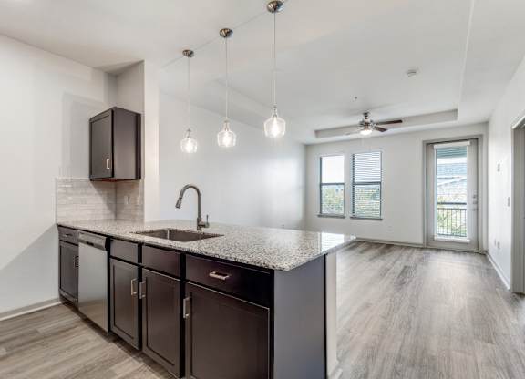 A kitchen with dark brown cabinets and a granite countertop.