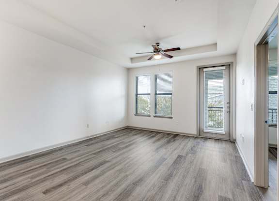 A room with a ceiling fan and sliding glass doors.