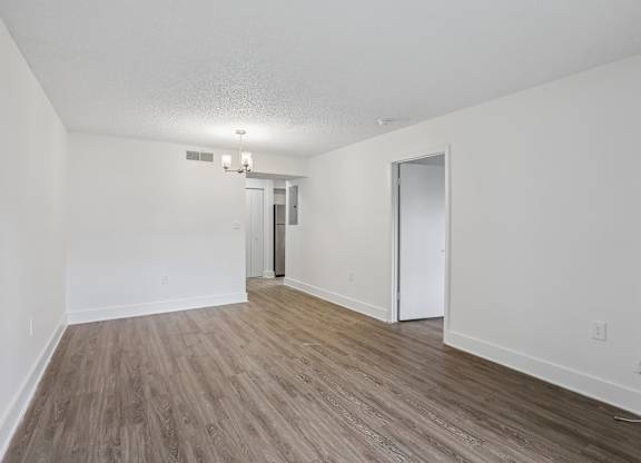 A room with a white ceiling, wooden flooring, and two doors.